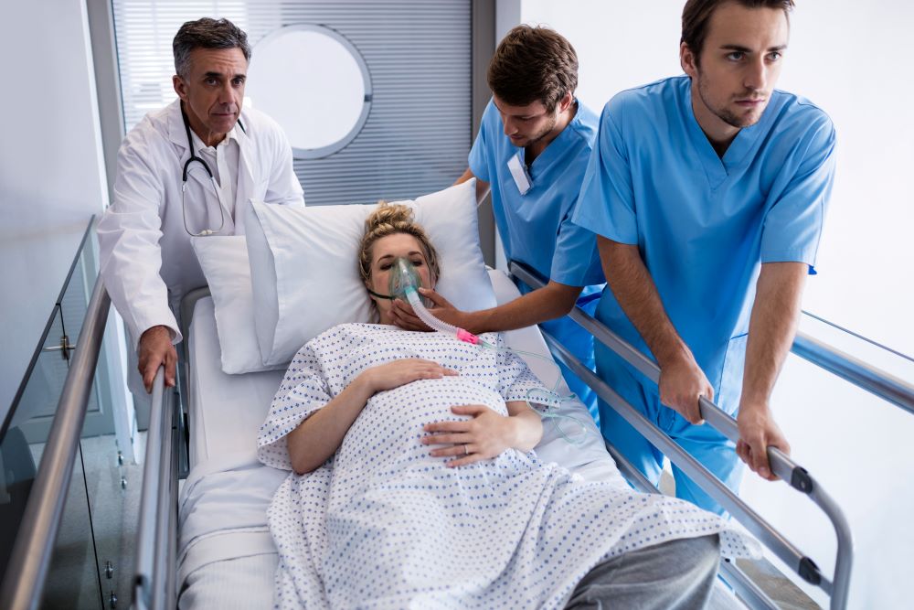 Team of doctors taking pregnant woman to operation theatre